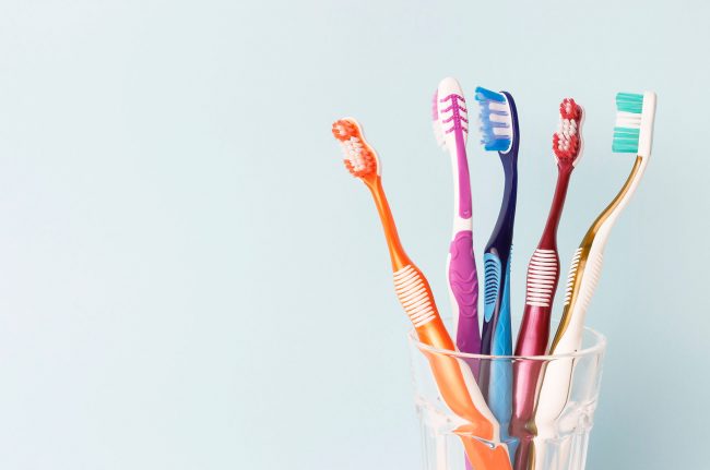 Five toothbrushes in a glass