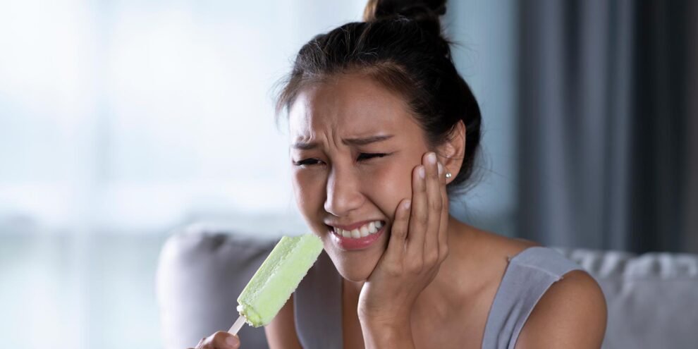 Women holding sore mouth after biting iceblock